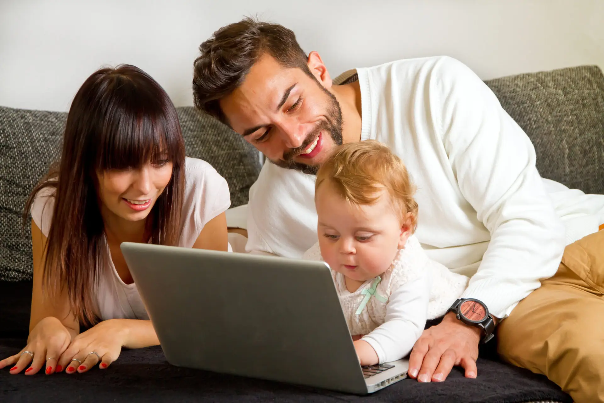 familia padres e hijo pequeño con jugando ordenador portátil